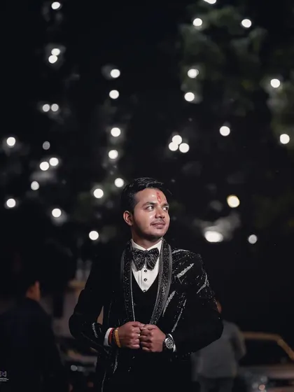 An outdoor groom portrait at night, with bokeh lights in the background. This creates a magical and celebratory atmosphere, perfect for capturing the groom's style during an evening event.