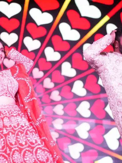 A fun, candid moment during a couple's performance against a backdrop of hearts. My choreography always includes moments for you to be yourselves and just enjoy dancing together.