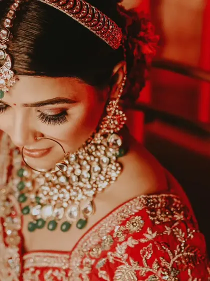 A close-up shot of the bride looking down, highlighting her intricate eye makeup and stunning bridal jewelry.