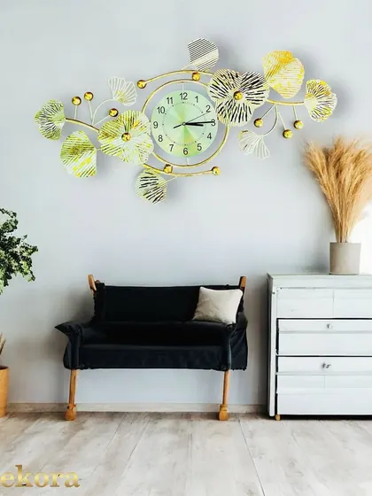 A horizontal metal wall clock featuring ginkgo leaf motifs in white and gold, creating a serene and artistic focal point above a bench or console.