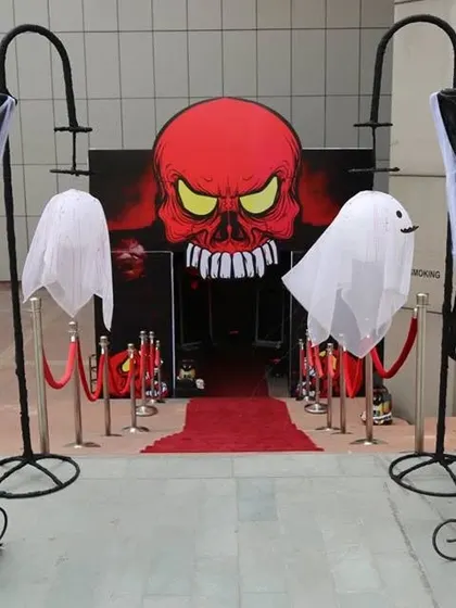 For a truly immersive Halloween party, we designed this spooky entrance. It features a giant skull backdrop, hanging ghost figures, and a red carpet walkway to set a dramatic and haunted tone right from the start.