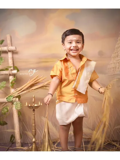 A joyful shot of the birthday boy in his traditional South Indian attire, surrounded by elements of a harvest theme.