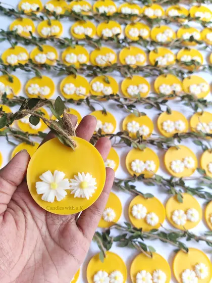 A close-up of the vibrant yellow soy wax sachets with white daisy details, part of the Haldi ceremony return gifts.