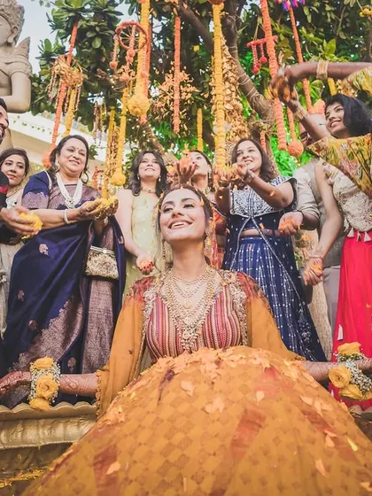 A moment of bliss for the bride during her Haldi ceremony, as loved ones shower her with flowers and blessings.