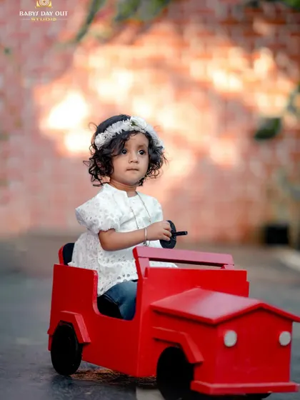 This little girl is ready for a drive in her bright red toy car. We have a variety of ride-on toys for fun, action-filled shots.