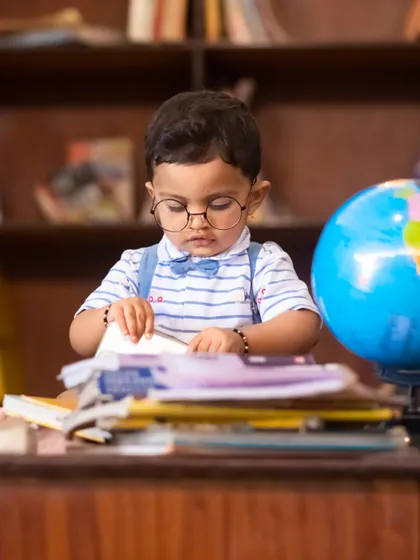 Deep in study, this little boy looks at a book with intense focus during his "little scholar" themed session.