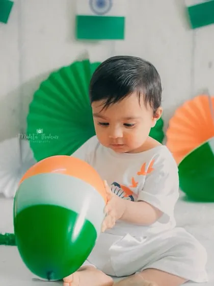 Focused on playing with a tricolor balloon, this shot captures a moment of quiet exploration. It shows that not every photo needs to be looking at the camera.