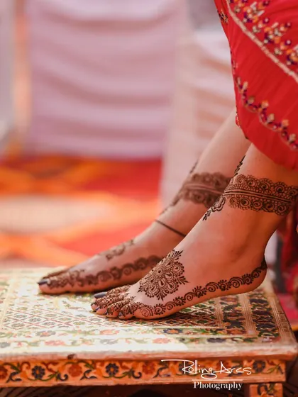 A detailed shot of the bride's feet, adorned with intricate Mehendi. This photo focuses on the traditional artistry and details that are part of the bridal preparation.