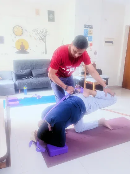I'm assisting a client in a deep backbend using a yoga strap and blocks. This supported approach allows for a safe and effective spinal stretch, improving flexibility and energy flow.