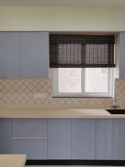 A close-up of the sink area, with the bamboo blind adding texture and warmth to the cool blue and beige color scheme.