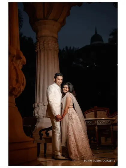 A romantic evening portrait of a couple at The Leela Palace. The grand architecture and soft lighting create a sophisticated and elegant mood.