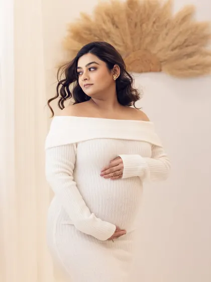 A thoughtful and serene portrait, with the mom-to-be looking out, bathed in soft studio light.
