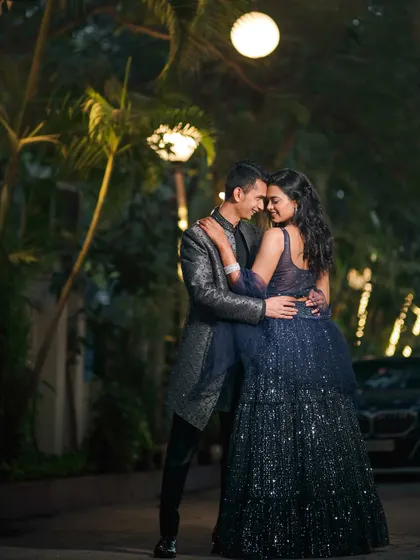A full-length shot of the couple in a tender embrace, surrounded by the warm glow of evening lights. The bride's sparkling gown and the romantic setting make this a truly cinematic portrait.