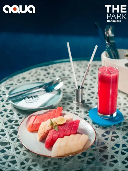 A healthy and refreshing fruit platter and juice at a poolside table. A perfect light snack to enjoy while lounging at Aqua.