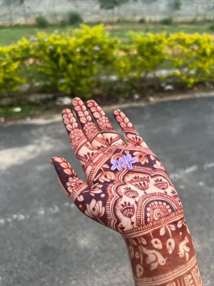 A close-up of the palm with a deep, dark stain, holding a delicate purple flower.