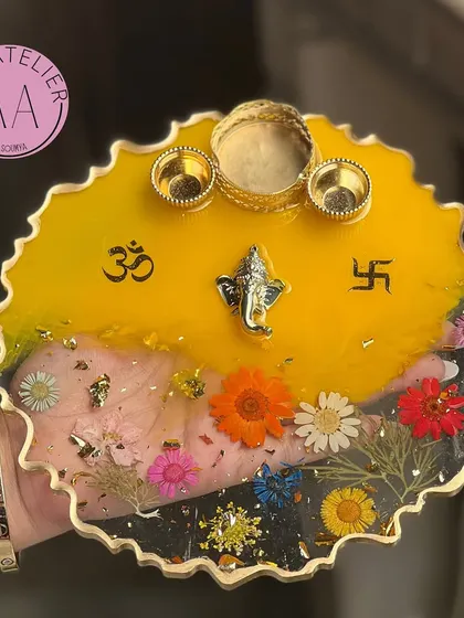 A beautiful resin Pooja Thali in a bright, auspicious yellow. It's adorned with real flowers, sacred symbols, and a Ganesha idol, perfect for your daily rituals.