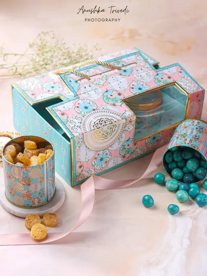 A whimsical pastel-colored Diwali hamper with decorative tins, styled with a flowing ribbon to add a touch of softness.