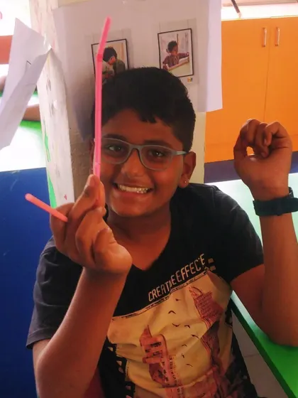 A smiling student shows off the simple helicopter toy he made using straws, a fun project that demonstrates the principles of lift.
