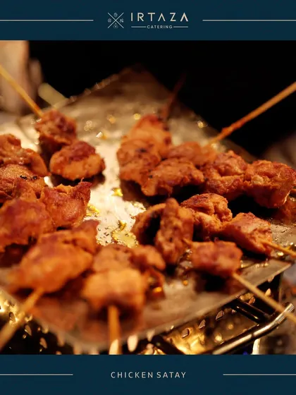 Juicy Chicken Satay skewers being grilled to perfection. This is a popular live station item that fills the air with an irresistible aroma and offers guests a taste of Southeast Asian cuisine.