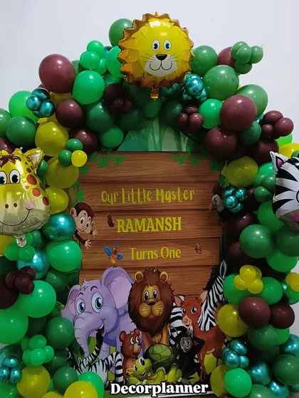 A closer look at the personalized jungle theme backdrop for Ramansh's first birthday. The vibrant greens and cute cartoon animals make it a cheerful and inviting centerpiece for the party.