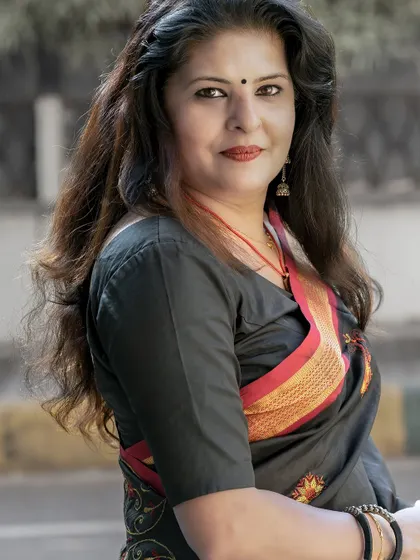 A close-up portrait in the black and red saree, focusing on the expression and the simple, elegant styling.