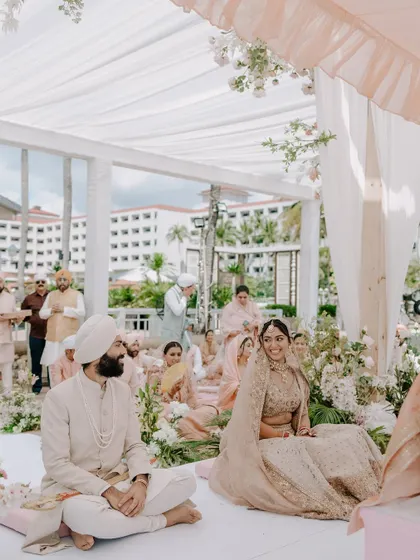 A candid moment during the Anand Karaj ceremony. The couple shares a look while seated, surrounded by the serene and beautiful decor.