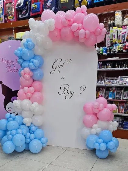 A "Girl or Boy?" gender reveal backdrop. This setup features an arched panel with a pink and blue balloon garland, perfect for a surprise moment.
