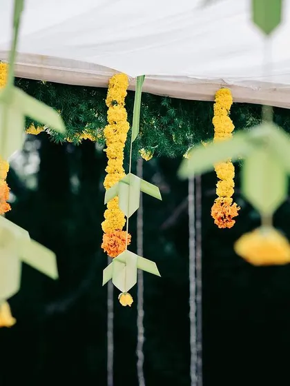 Hanging decorations made from marigolds and folded palm leaves add a unique, handcrafted element to the overall decor.