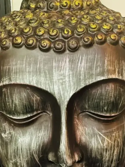 This Buddha statue features a striking metallic finish, with a brushed silver face and gold-accented hair. This finish adds a touch of modern glamour to the traditional form.