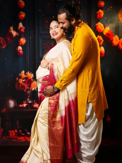 A loving embrace captured during a traditional themed shoot. The couple's coordinated ethnic wear and the festive backdrop of marigolds create a warm and timeless memory.