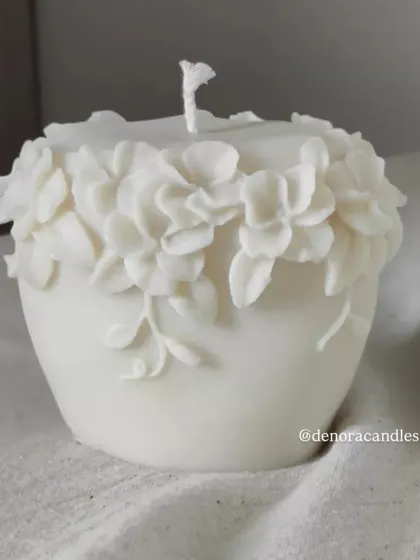 A shorter, pot-shaped floral pillar candle with a crown of 3D flowers.