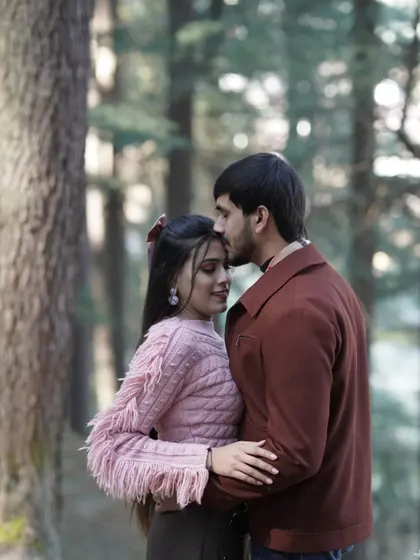 A tender moment in a pine forest in Manali, with the groom kissing his bride's forehead, capturing the serenity of the woods.
