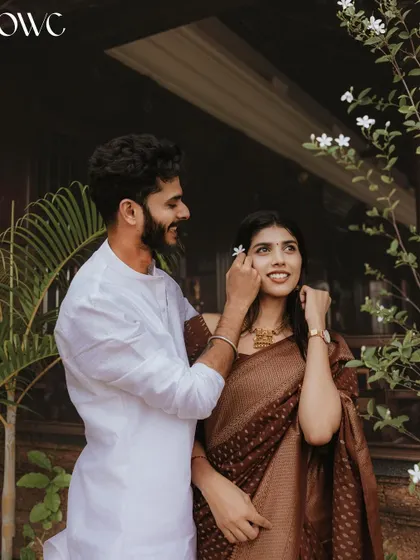 A gentle moment where the groom-to-be places a flower in his partner's hair, a simple yet deeply romantic gesture from their pre-wedding session.