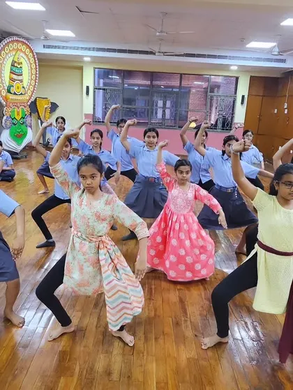 A wide shot of a school workshop, showing a large group of students learning Chhau together.