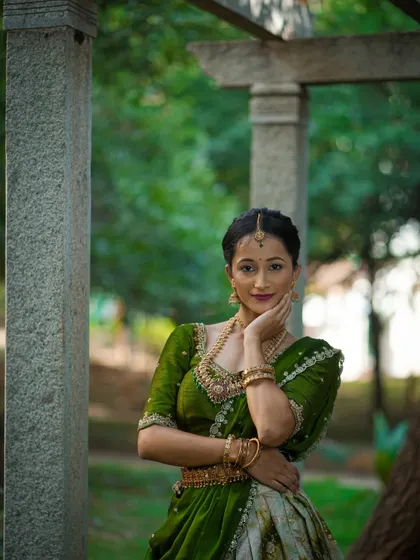 A close-up portrait of a client in her custom green half saree, radiating peace and harmony.