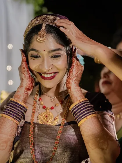 A joyful, candid moment as the bride gets her headpiece adjusted. Her makeup is flawless, and her smile is radiant.