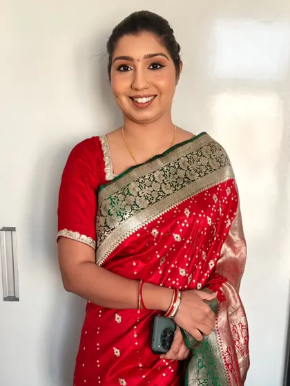 HD party makeup paired with a traditional red saree. The look is completed with a neat bun and professional saree draping.