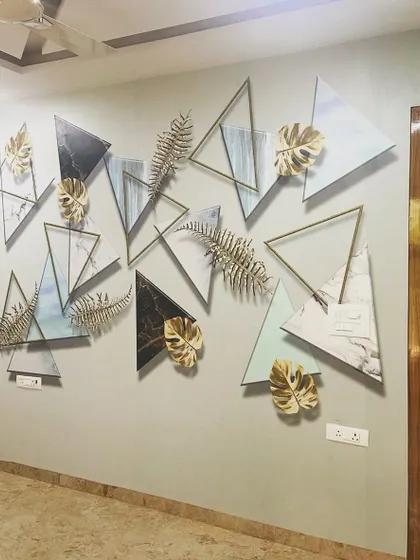 This unique wall art combines triangular wallpaper panels with 3D golden leaf accents. It's a custom creation that mixes different materials to produce a one-of-a-kind feature wall.