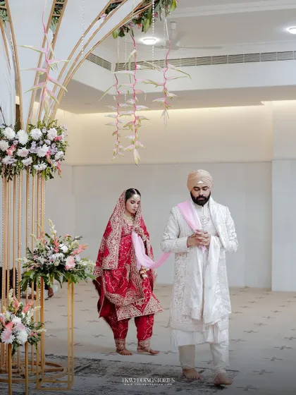The bride and groom during their entrance at the wedding ceremony, showcasing the beautiful decor and their grand outfits.