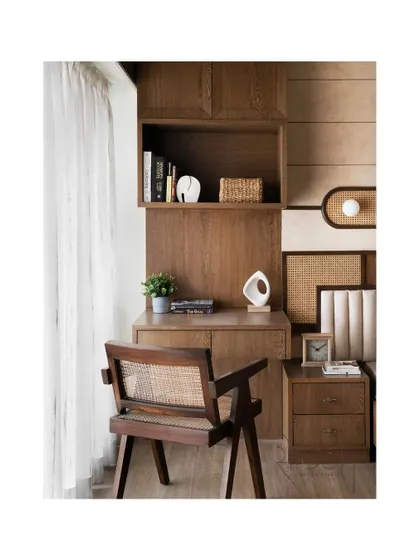 A cozy study corner integrated into the parent's bedroom. The custom desk and chair, made from dark wood and cane, continue the room's vintage, natural aesthetic.