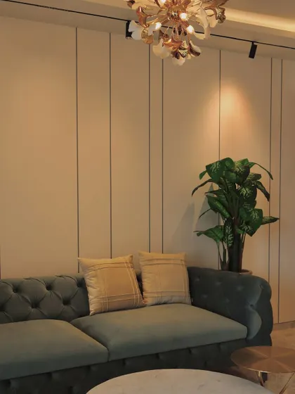 A detail shot of a living room, focusing on the elegant chandelier and the simple lines of the paneled wall.