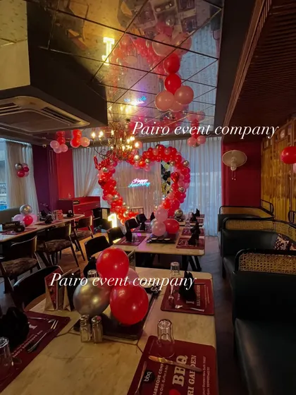 A wide-angle view of the restaurant decorated for a 1st anniversary, showing how the central heart arch and ceiling balloons transform the entire space.