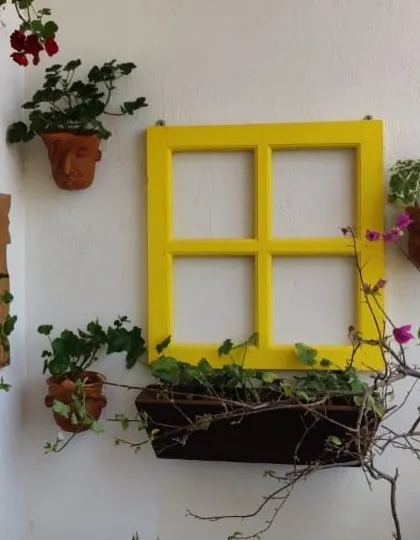 I love getting creative with wall spaces. For this balcony, I used a bright yellow repurposed window frame as a centerpiece, surrounded by terracotta wall planters to turn a plain wall into a vibrant vertical garden.