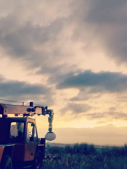 A shot from a film set, showing a crane with a light set up against a sunset sky. This gives a glimpse into the scale of production and lighting setups I work with.
