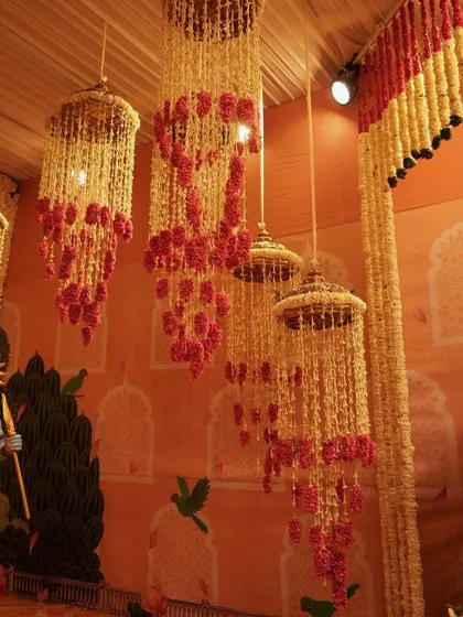A collection of hanging floral chandeliers, or 'jhoomars', made from fragrant tuberose and colorful carnations. They fill the air with beauty and a divine scent.
