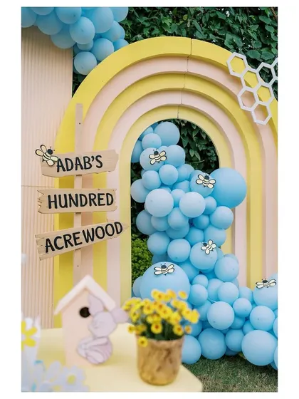 A close-up of the Hundred Acre Wood sign and the cascading blue balloon garland, key elements of our Winnie the Pooh party decor.