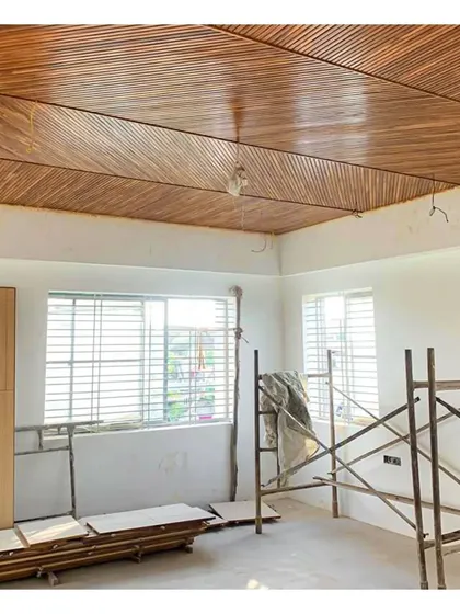 A work-in-progress shot of a bedroom ceiling with intricate teak wood paneling laid in a geometric pattern.