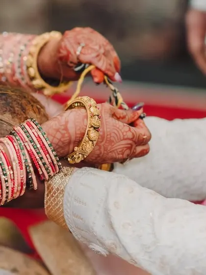 A close-up detail shot of hands during a wedding ritual, symbolizing the union and blessings.