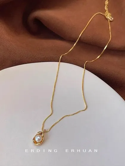 A beautiful necklace featuring a single pearl nestled in an ornate, nest-like gold pendant. This is a unique and artistic piece for any jewelry lover.