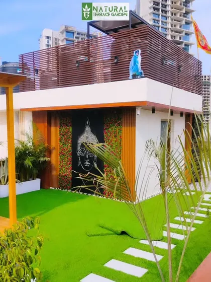 A completed terrace project in Gwal Pahari, Gurgaon, featuring a wooden pergola, artificial lawn, and a feature wall with a Buddha motif.